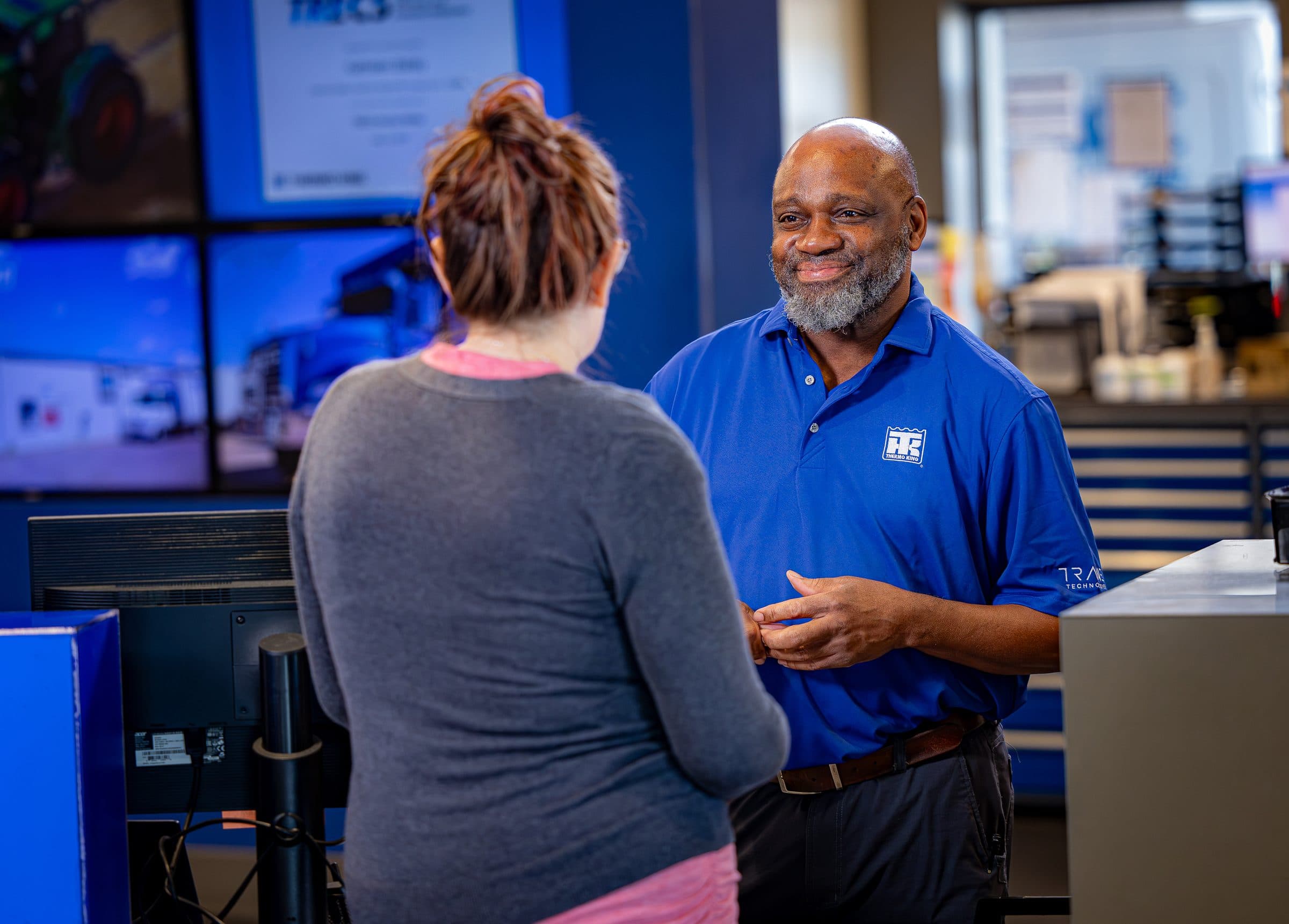 A service advisor in a Thermo King shirt talking with a customer at a service desk